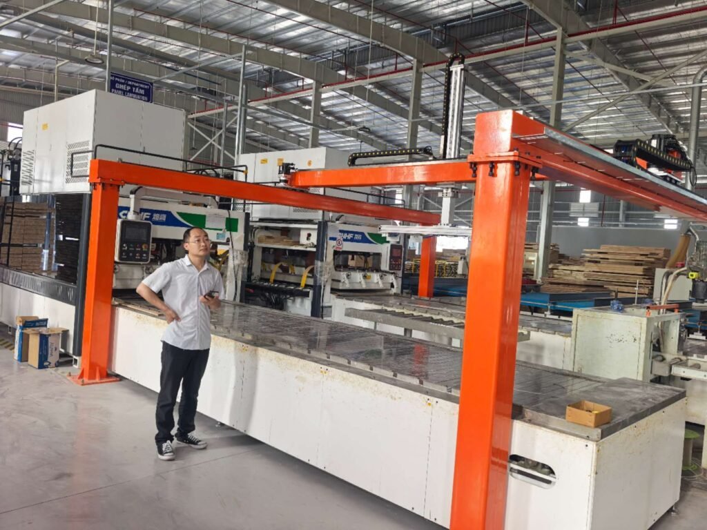 Orange gantry loading and unloading machine integrated with a high-frequency wood panel press line in a modern factory