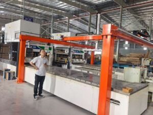 Orange gantry loading and unloading machine integrated with a high-frequency wood panel press line in a modern factory